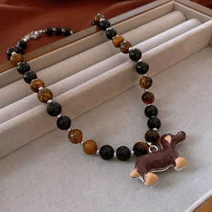 Detail of beaded necklace with tiger eye stones and a brown dachshund enamel pendant