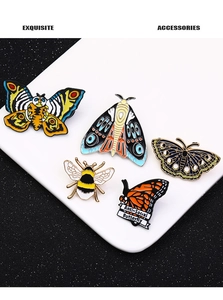 Detailed view of 5 butterfly and moth enamel pins on a professional display tray