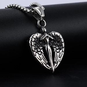 Detail shot of vintage silver heart sword and wing pendant on dark leather texture