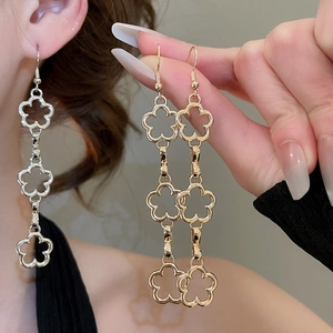 Detailed close-up of hollow flower tassel earrings in gold and silver finish