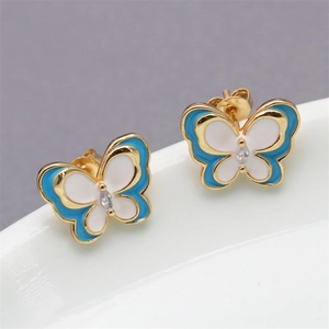 Detail of gold butterfly stud earrings with blue and white enamel and a tiny clear crystal