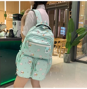 Side view of mint green backpack with cute bear print worn in a cafe setting