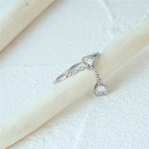 Detail of silver heart ring featuring a hollow heart and dangling zircon heart charm