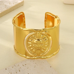 Macro detail of vintage gold sun face pattern on geometric textured wide bangle