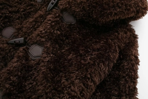 Detailed macro view of dark brown faux fur texture with black toggle button and leather patch