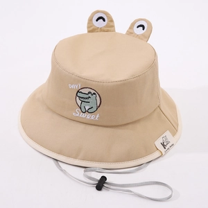Détail du chapeau bébé avec yeux 3D et broderie de dinosaure en couleur kaki