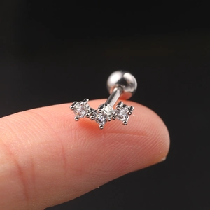 Macro shot of silver zircon helix piercing stud on fingertip showing precise small size
