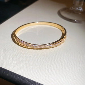 Macro shot of 18k gold plated bangle featuring a crisscross design with pavé set cubic zirconia