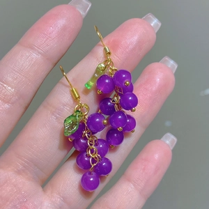 Detailed close-up of grape-shaped purple drop earrings with green leaves and gold hooks