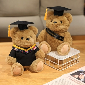 Doctoral teddy bears in graduation gowns and caps on a wooden desk for commemorative gifts