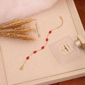 Detailed close-up of golden chain bracelet with red lip charms on linen texture