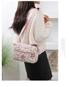 Polka dot crossbody bag with adjustable pink strap shown on model in stylish indoor setting