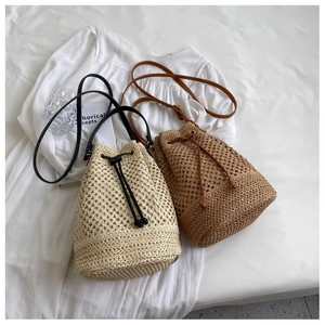 Detailed view of hollow woven straw bucket bags in beige and brown with leather straps