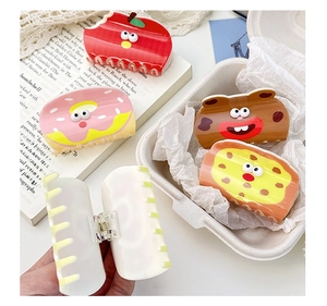 Detail shot of acrylic hair claws in apple, donut, monkey, and pizza shapes