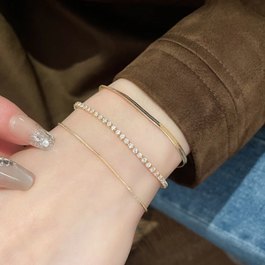 Three-piece layered gold bracelet set with flat snake chain and white zircon tennis chain