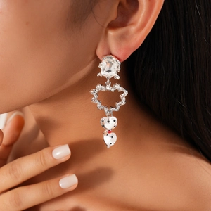 Détail de boucles d'oreilles argentées avec cristal et breloques cœurs à pois noirs