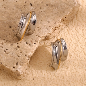 Close-up of knight helmet earrings with dual-tone gold and silver irregular curves