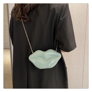 Detailed view of mint green lip-shaped crossbody bag with gold chain strap on model