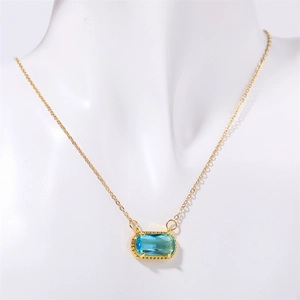 Nahaufnahme einer goldenen Halskette mit ovalem blauem Edelstein auf einer weißen Büste