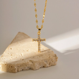 Macro view of 18K gold cross necklace with white zircon on a natural stone base
