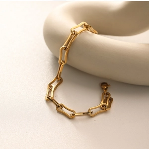Detailed view of 18k gold plated stainless steel chain bracelet on white ceramic decor