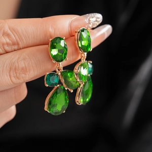 Close-up of vintage geometric teardrop earrings with green stones in gold setting