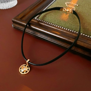 Macro shot of gold starburst pendant with zircon on a vintage black leather choker necklace