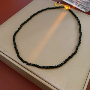 Detail of minimalist black faceted bead necklace with gold-plated adjustable clasp chain