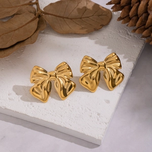 Detailed view of gold bow knot stud earrings with metallic luster on a vintage background