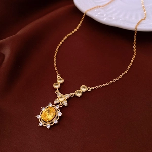 Close-up of gold-plated necklace with vintage pendant featuring a large yellow gemstone