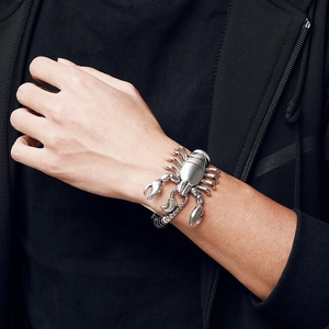 Close-up of a silver titanium steel scorpion bracelet worn on a man's wrist