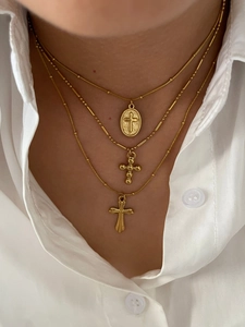Close-up of triple layered gold cross necklaces on model with white shirt