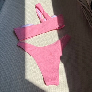 Detail of pink one-shoulder bikini with embossed floral texture and high-cut bottom