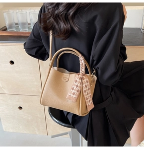 Detail of light brown bucket bag with lychee texture leather and plaid silk scarf decoration