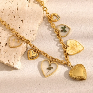 Dettaglio di ciondoli a cuore in oro 18K con fiori pressati e strass su catena dorata