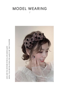 Brown satin headband with black flocked polka dots and a bow worn by a model