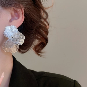 Gros plan détaillé de grandes boucles d'oreilles fleurs évidées en argent tissé