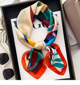 Close-up of a multi-color geometric silk scarf folded as a bow on a stylish black tray