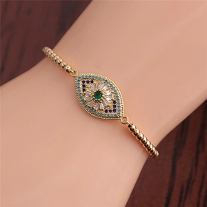 Macro shot of gold-plated evil eye bracelet with green zircon on wooden background