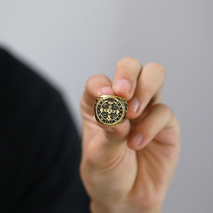 Detailed close-up of a gold Saint Benedict medal religious cross ring in titanium steel