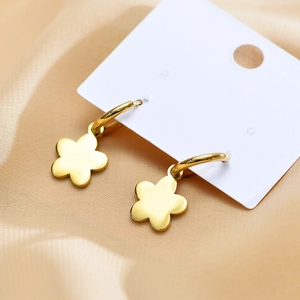 Close-up of golden flower charm hoop earrings on elegant silk background fabric