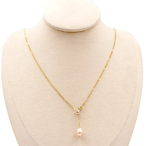 Collier élégant en titane doré avec une perle goutte rose clair sur un présentoir