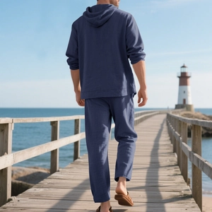 Rear view of navy blue linen hooded shirt and pants set for men on a beach boardwalk