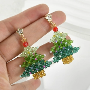 Macro detail of handmade green beaded Christmas tree earrings with a sparkling gold star