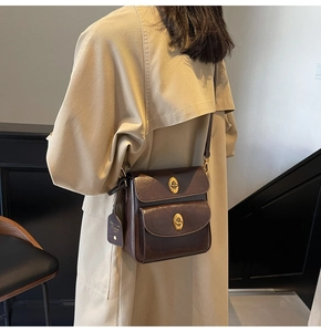 Close-up of vintage brown crossbody bag featuring dual gold metal twist-lock buckles