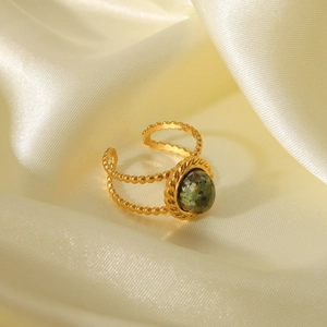 Macro detail of gold vintage ring with green natural stone on silk background