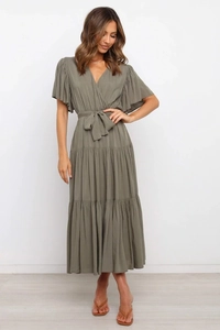 Detalle de vestido verde con cuello en V, mangas de volante y falda plisada