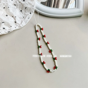 Close-up of handmade cherry bear phone strap with white pearls and red beaded charms