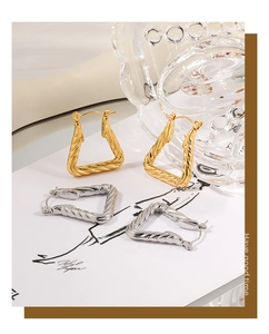 Detailed close-up of geometric twisted triangle hoop earrings in gold and silver finish