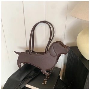 Detail of dachshund-shaped shoulder bag in dark brown smooth finish on an art book
